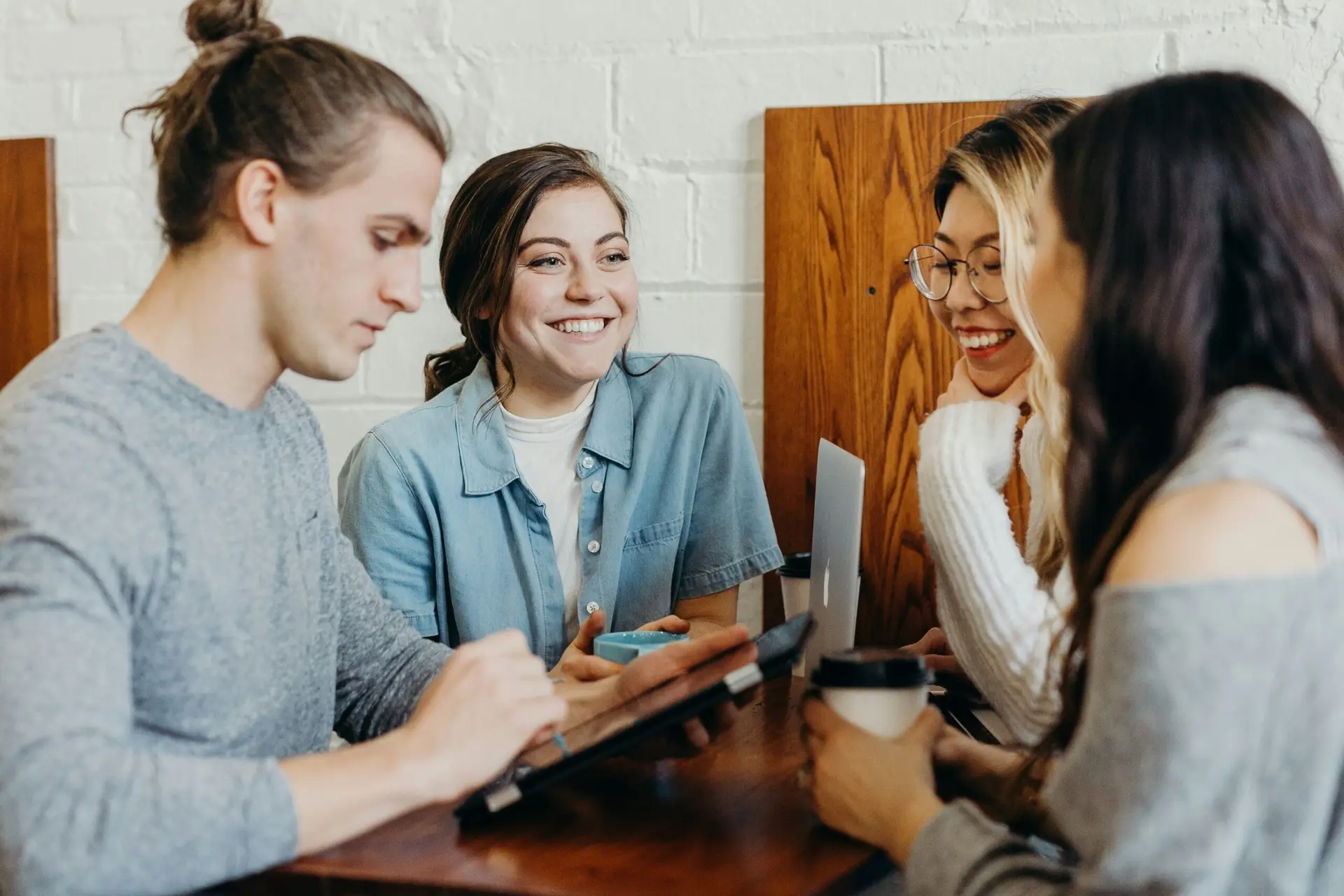 Group of four happy students talking and working